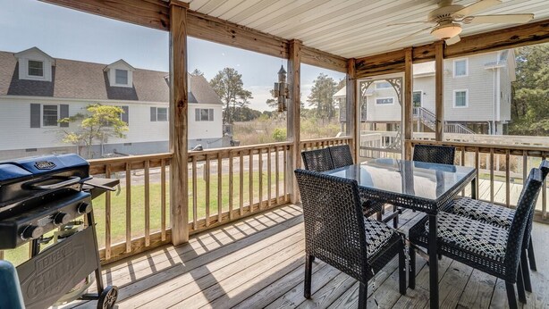 Eine überdachte Terrasse mit Grill, Tisch und Stühlen.