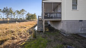 A two-story house with a balcony, a wooden deck, and a concrete foundation.