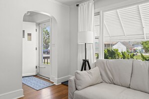 Een moderne woonkamer met een bank, een vloerlamp en uitzicht op buiten.