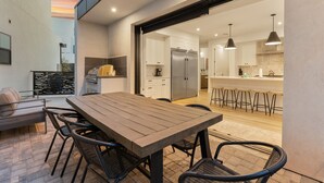 A modern kitchen with white cabinets, a stainless steel refrigerator, and a bar area with stools.