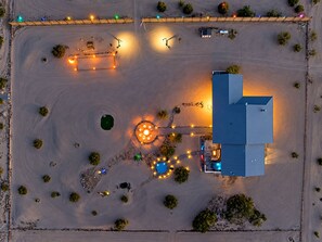 An aerial view of a property with a large building, a swimming pool, and a well-lit patio area.