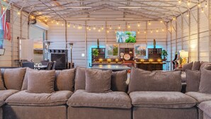 A spacious living area with a sectional sofa, a dining table, and a kitchen area in the background. - The Ranger Station + Club House w/Hot Tub (Joshua Tree)
