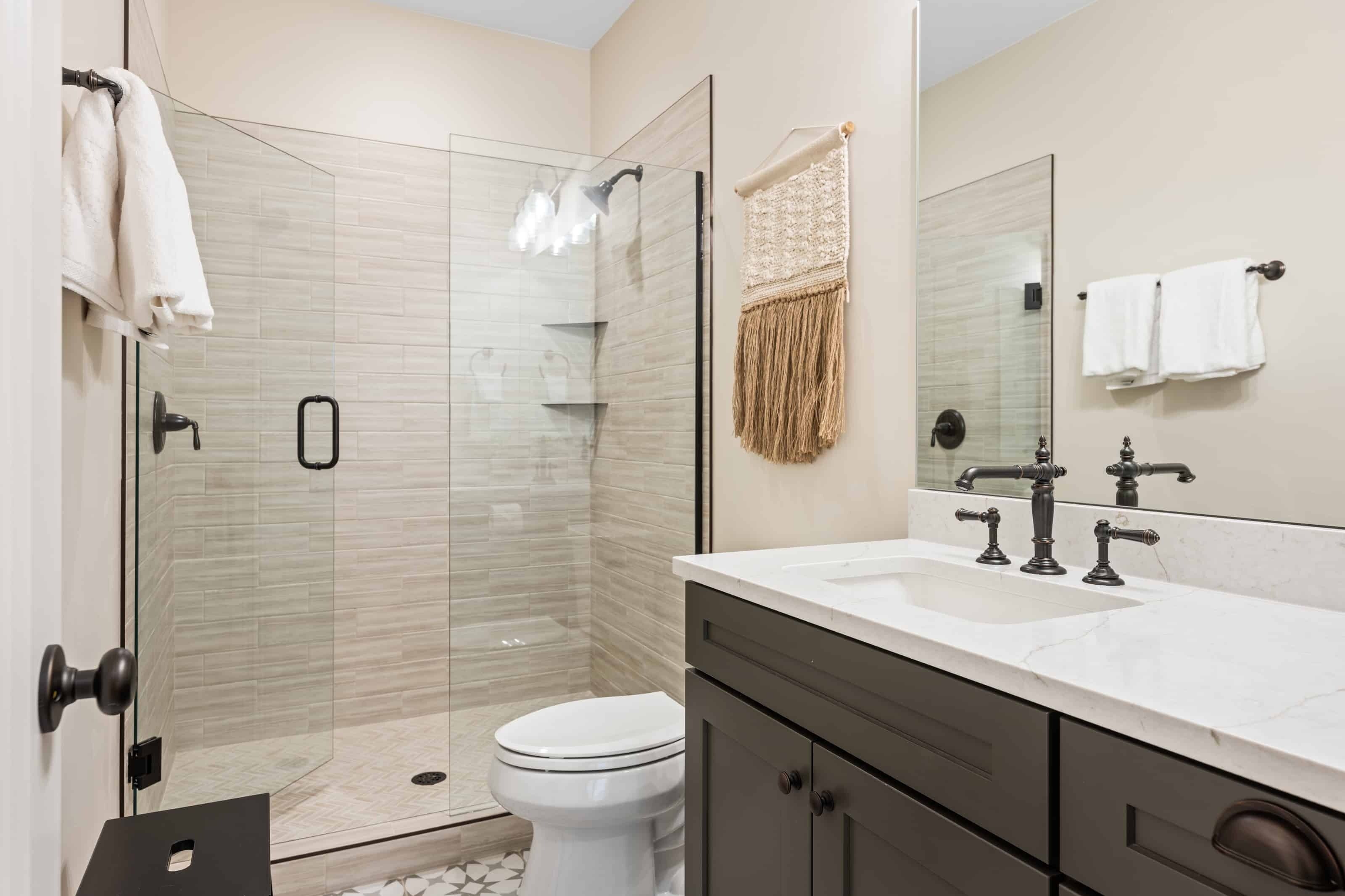 Une salle de bain moderne avec une douche à parois de verre, des toilettes blanches, un meuble-lavabo avec un miroir et un porte-serviettes.