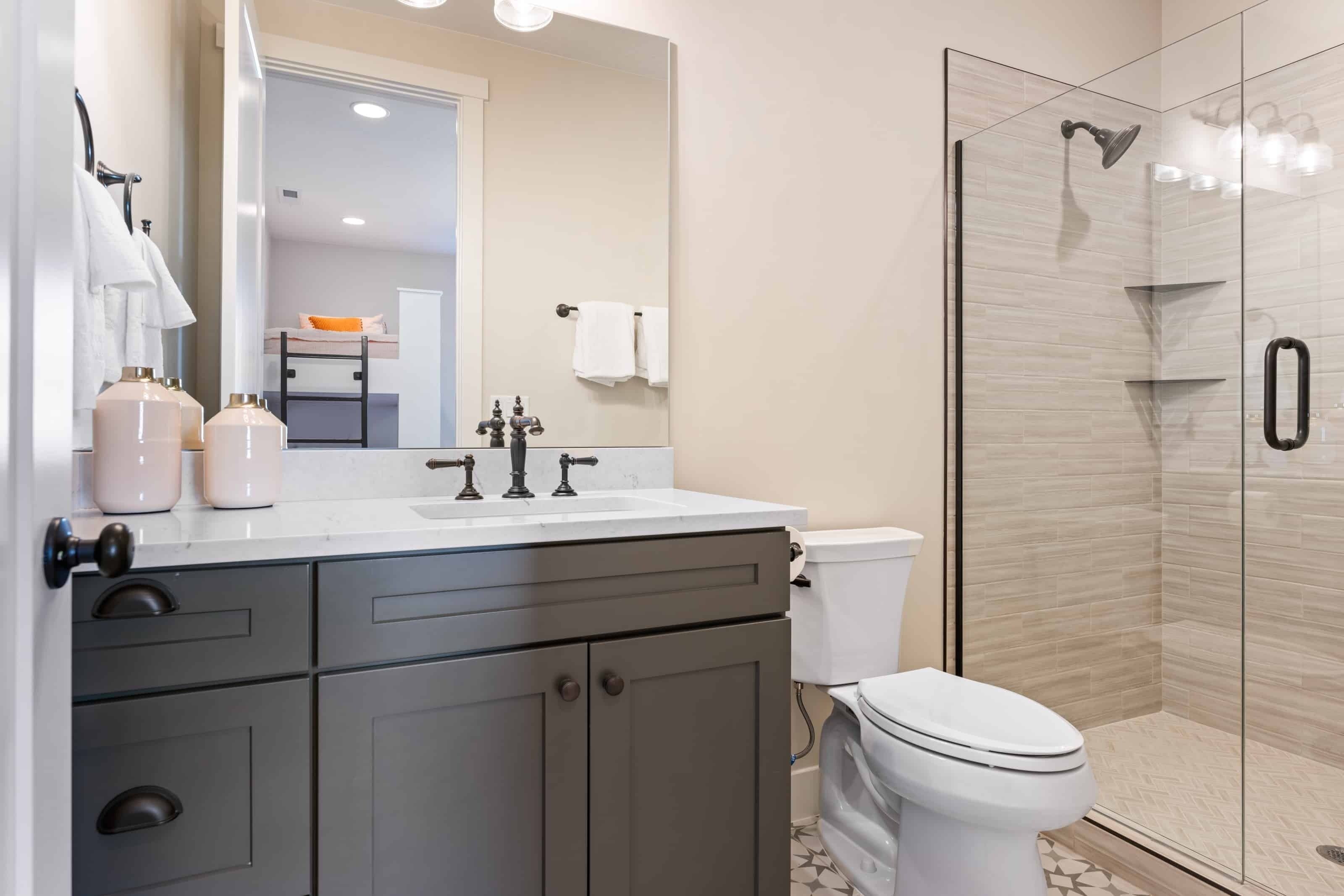 Un baño moderno con cabina de ducha de vidrio, inodoro blanco y tocador con espejo.