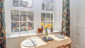 A dining area with a round table, two chairs, a vase with flowers, and a wooden heart-shaped decoration. - 4 Pulmans Place (Halifax)