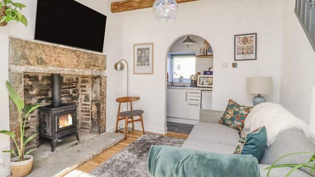 A cozy living room with a stone fireplace, a sofa with decorative pillows, a hanging light fixture, and a view into the kitchen. - 4 Pulmans Place (Halifax)