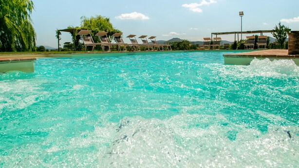 Une piscine à l’eau claire, entourée de chaises longues et agrémentée d’une pergola.