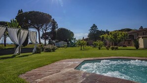 Une piscine bordée de briques, entourée d’une pelouse bien entretenue et d’arbres.