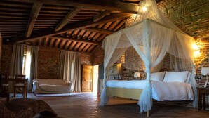 Une chambre à coucher rustique avec un lit à baldaquin, une chaise en bois et un canapé en osier.