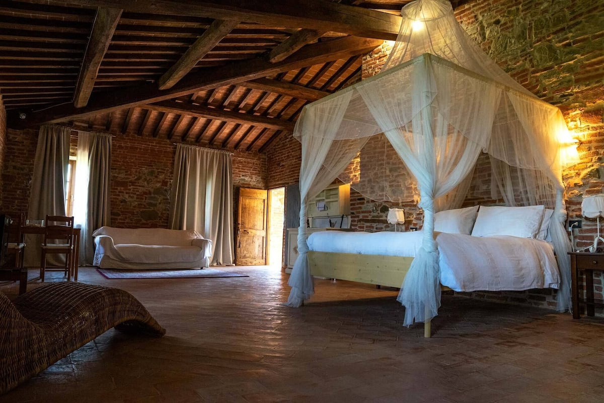Ein rustikales Schlafzimmer mit einem Himmelbett, einem Holzstuhl und einer Korbschaukel.