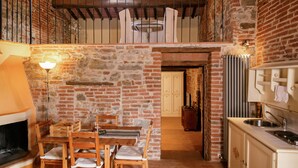 Une cuisine rustique avec un mur en pierre, des meubles en bois et une vue sur l’étage supérieur.