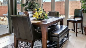 Een eetgedeelte met een tafel gedekt voor vier personen, omringd door stoelen, een kroonluchter en uitzicht op een woestijnlandschap door grote ramen.