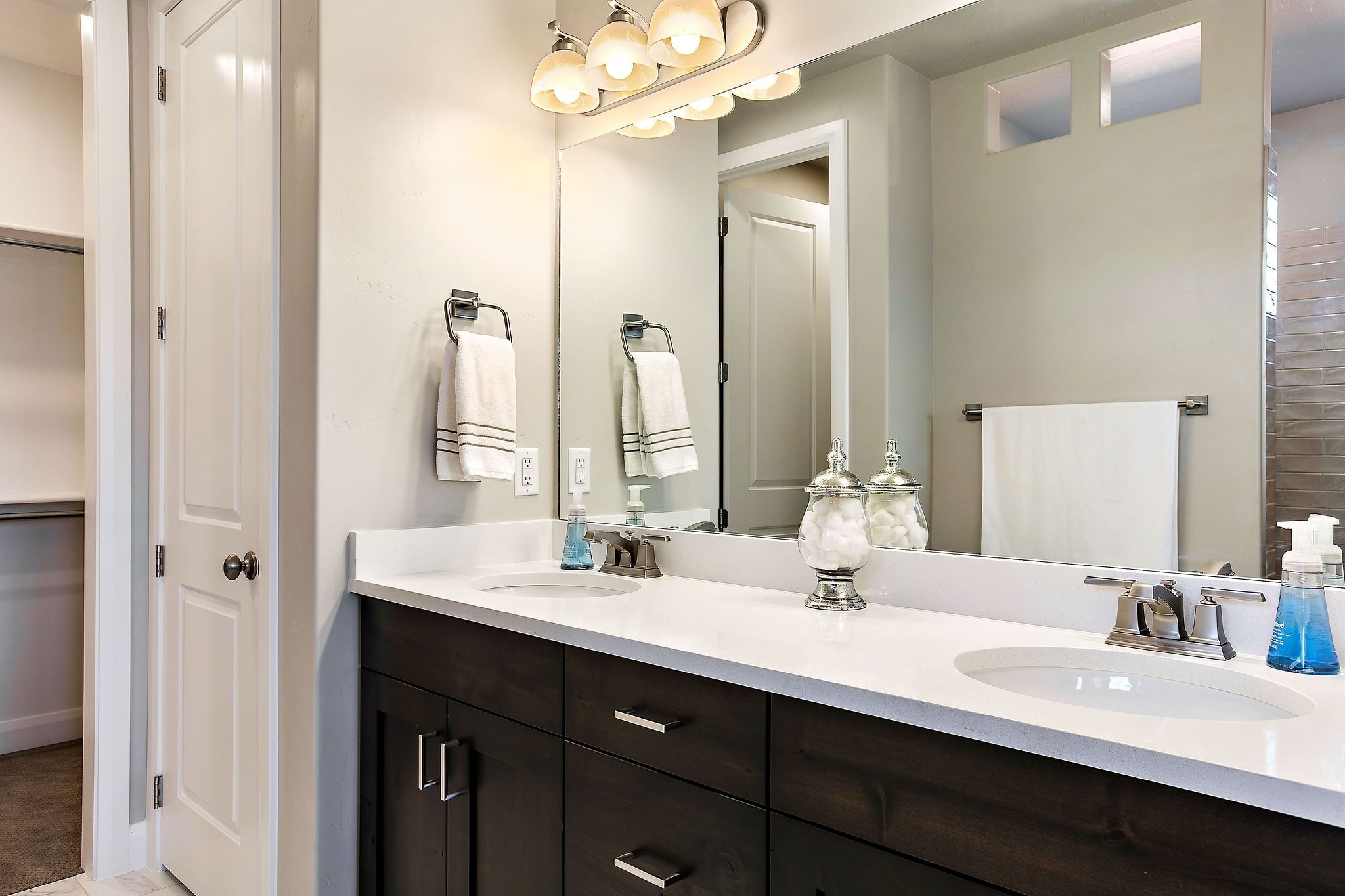 A bathroom with two sinks, dark cabinets, and a large mirror.