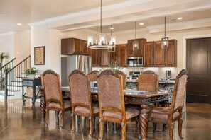 A spacious kitchen with wooden cabinets, a stainless steel refrigerator, and a dining area with a round table and ornate chairs. - Palazzo #f11 5 Bedroom Home (Hurricane)