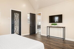 A bedroom with a bed, a TV mounted on the wall, and a console table with a plant. - Palazzo #f11 5 Bedroom Home (Hurricane)