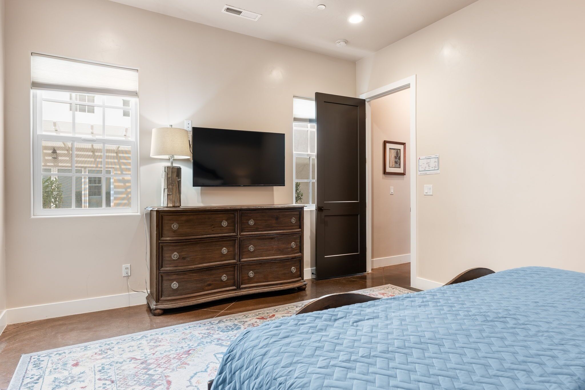 A bedroom with a bed, dresser, TV, and a door.