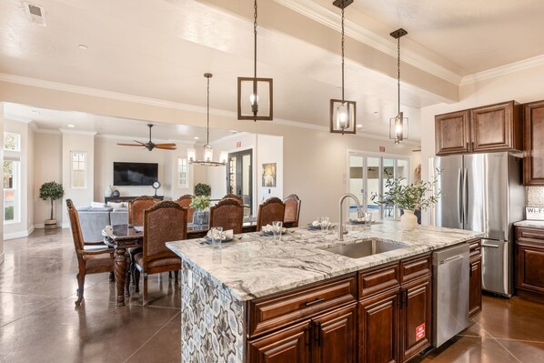 A spacious kitchen with a large island, wooden cabinets, and a stainless steel refrigerator. - Palazzo #f11 5 Bedroom Home (Hurricane)