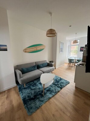 A modern living room with a grey sofa, a white coffee table, and a blue rug.