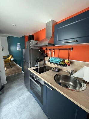 A compact kitchen with a built-in oven, a stainless steel sink, and a microwave.