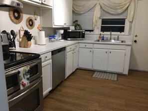 A kitchen with white cabinets, a microwave, a dishwasher, and a stove.