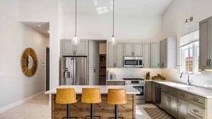 A modern kitchen with a central island, stainless steel appliances, and pendant lighting. - The Wanderer 2 Bedroom Home (Hurricane)