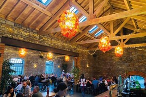 A spacious indoor venue with stone walls, wooden beams, and hanging floral chandeliers. - Stunning 2 bed coastal apartment (Llanelli)