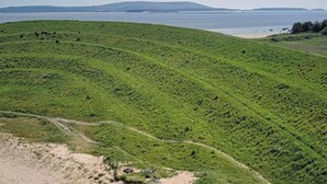 Un paisaje costero con colinas verdes ondulantes, una playa arenosa y una vista despejada del mar.