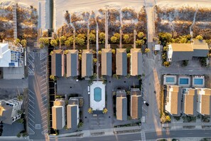 An aerial view of a residential area with multiple apartment buildings, a central swimming pool, and a parking lot. - Southern Belle: Oceanfront | Surfside Beach Vacation Rental (Surfside Beach)
