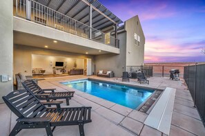 A modern outdoor pool area with lounge chairs, a covered seating area, and a view of the sunset. - The Ann Marie #f1 6 Bedroom Townhouse (Hurricane)
