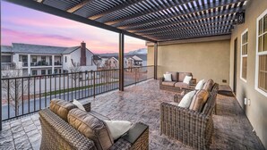 A covered outdoor patio with wicker furniture and a view of buildings in the background.
