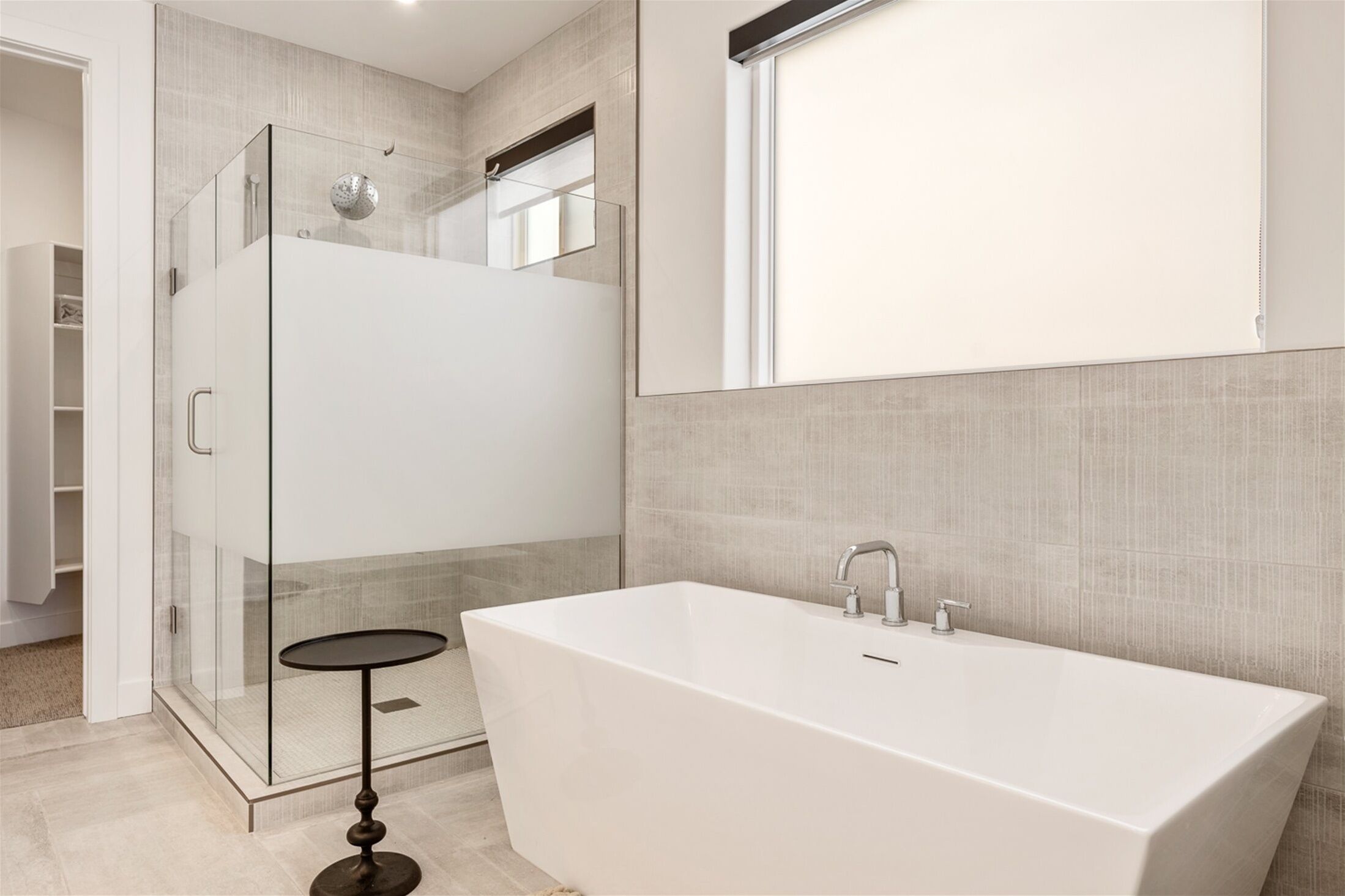 Une salle de bain moderne avec une douche à parois de verre, une baignoire sur pieds et un grand miroir.