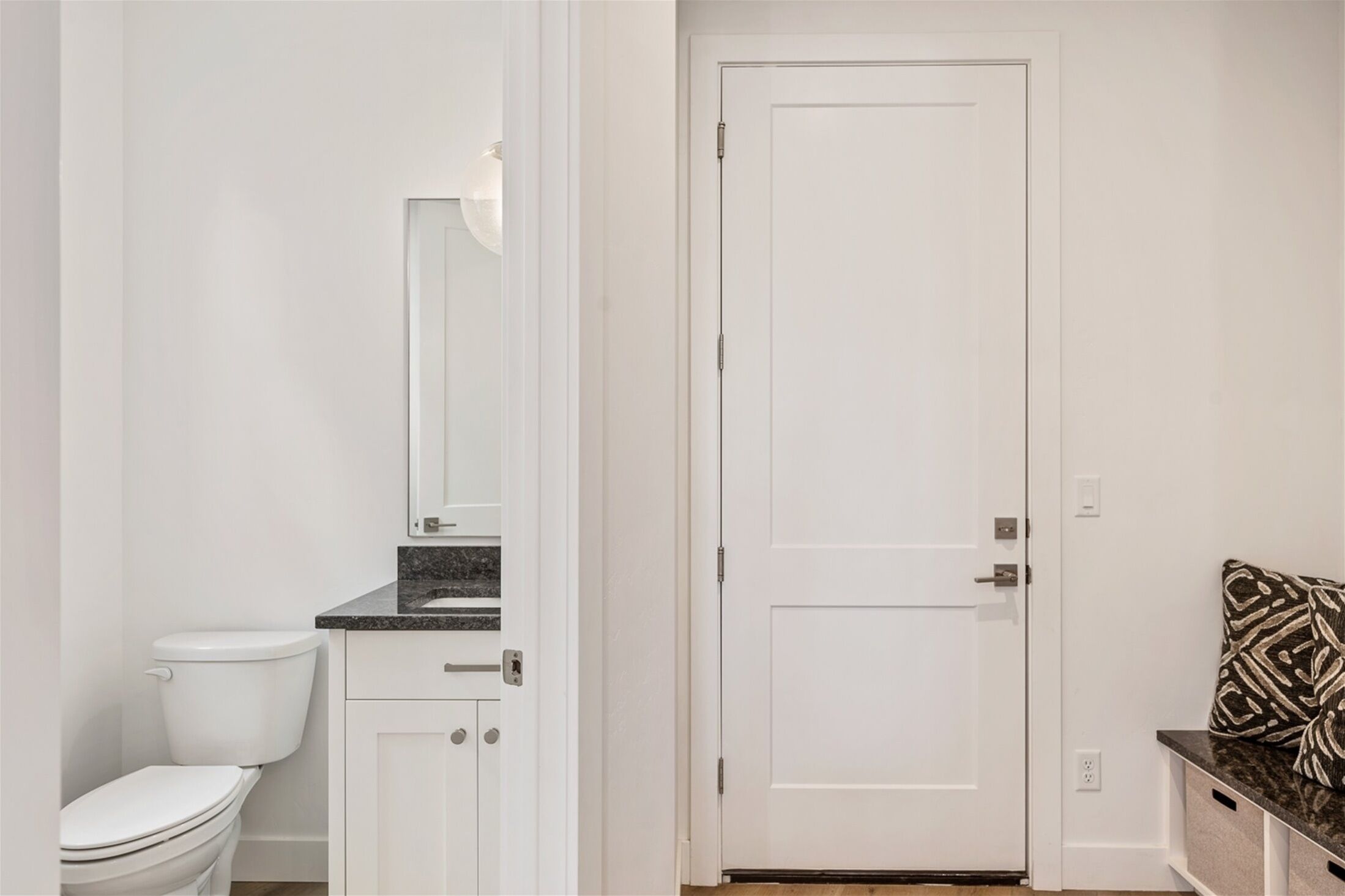 A bathroom with a white toilet, a mirror, and a door.