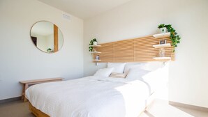 Ein Schlafzimmer mit einem hölzernen Bettgestell, einem runden Spiegel und einem eingebauten Regal mit Pflanzen.