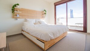 Ein modernes Schlafzimmer mit einem hölzernen Bett, einer eingebauten Pflanzenwand und einer großen Glasschiebetür nach draußen.