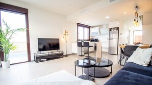 Ein modernes Wohnzimmer mit Fernseher, Sofa und Essbereich.