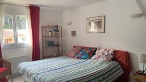 Une chambre à coucher avec un lit, une bibliothèque, une fenêtre avec des rideaux et un tableau accroché au mur.
