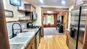 A compact kitchen with a stainless steel refrigerator, a microwave, a sink, and wooden cabinets. - Lynnhurst Resort-Private cabin on Kentucky Lake with Hot Tub (Murray)