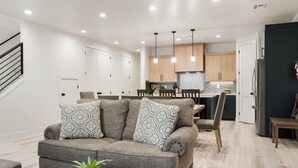 A modern living room with a grey sofa, patterned cushions, and a coffee table with a plant and a tray. - Lula Inez Game Paradise 4 Bedroom Townhouse (St. George)