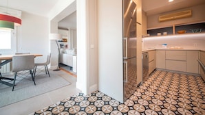 Una cocina moderna con piso estampado, un refrigerador y un comedor con mesa y sillas.