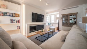 Una sala de estar moderna con chimenea, un televisor de pantalla plana, una estantería y un sofá cómodo.