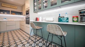 Una cocina moderna con piso estampado, dos taburetes de bar, una cafetera y un microondas.
