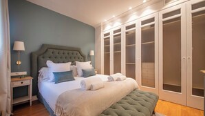 Un dormitorio con una cama grande, una mesita de noche, un aparador y un vestidor.