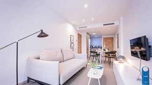 A modern living room with a sofa, a coffee table, a floor lamp, and a TV mounted on the wall.