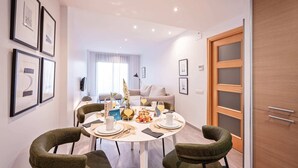 A dining area with a round table set for four, surrounded by green upholstered chairs.