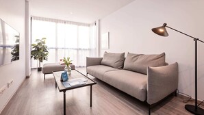 Ein modernes Wohnzimmer mit einer Couch, einem Couchtisch, einer Stehlampe und einem Blumentopf.