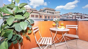 Un balcon avec une table dressée pour deux personnes, une plante en pot et une vue sur la ville.