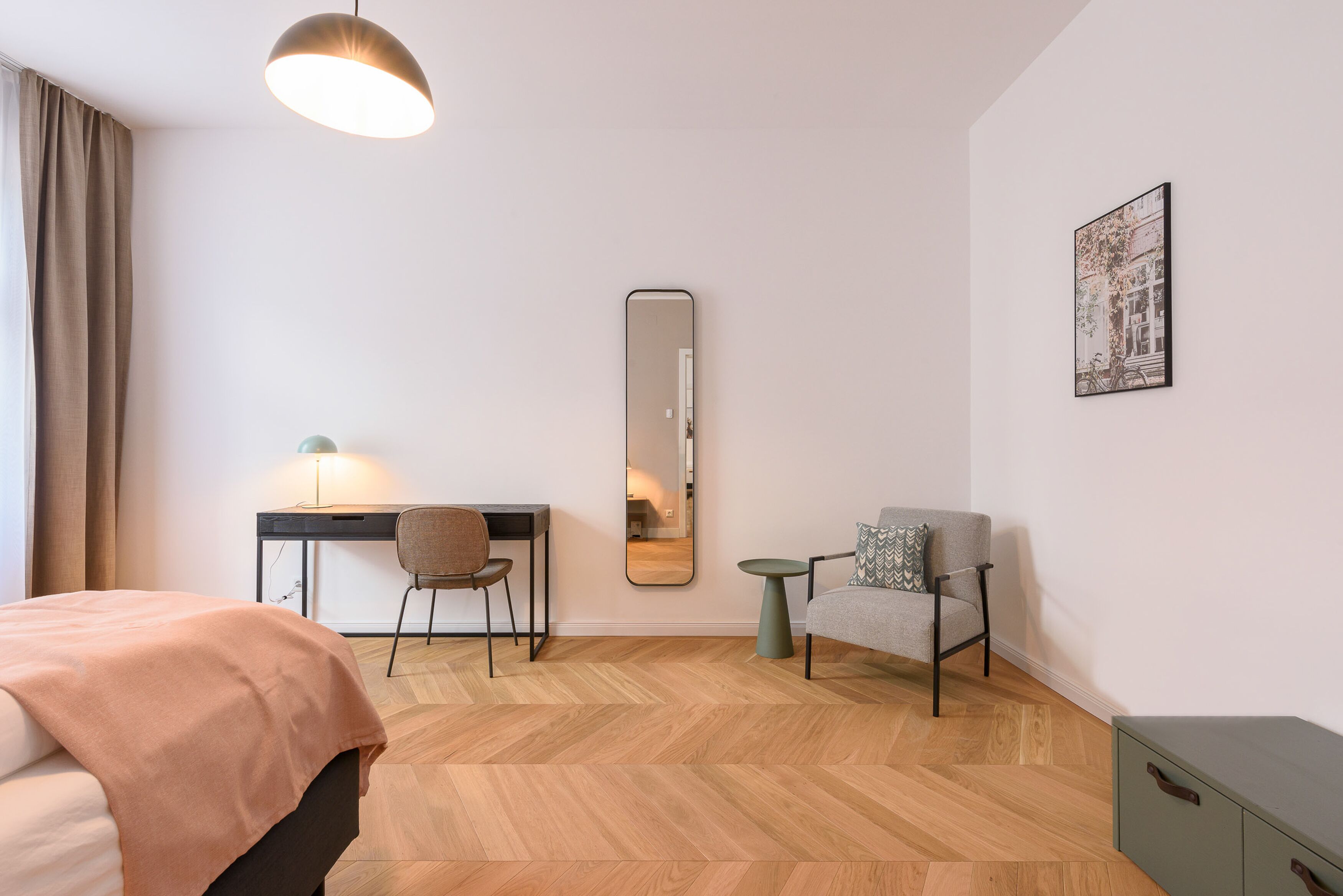 Een moderne hotelkamer met een bed, bureau, stoel en een klein tafeltje.