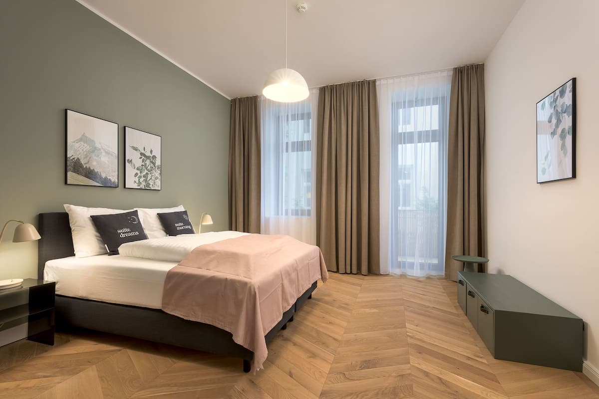 Une chambre à coucher moderne, avec un lit, des tables de chevet, une commode, un bureau et une grande fenêtre avec des rideaux.