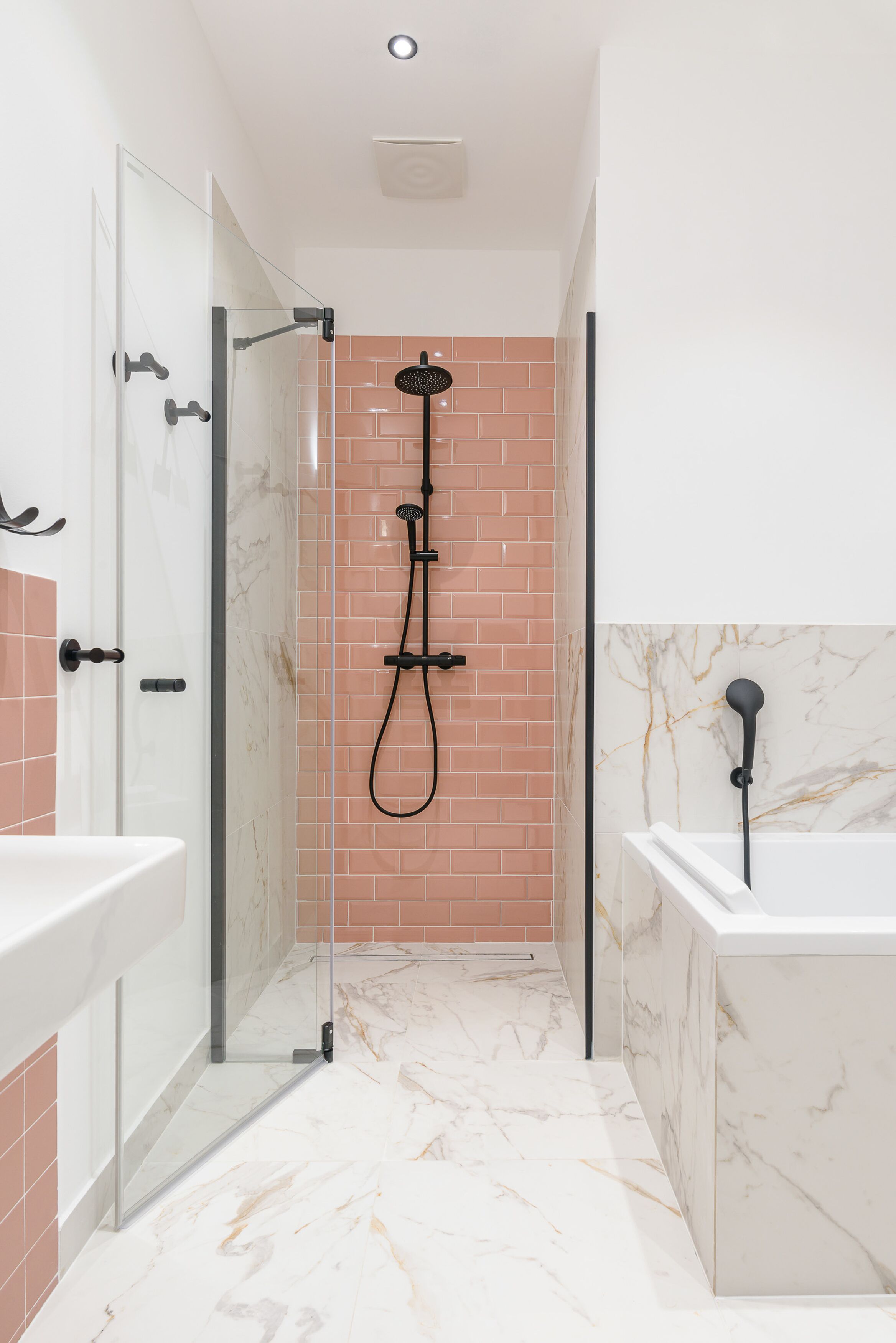 Ein modernes Badezimmer mit einer gläsernen Duschkabine, einer weißen Badewanne und einem Marmorboden.