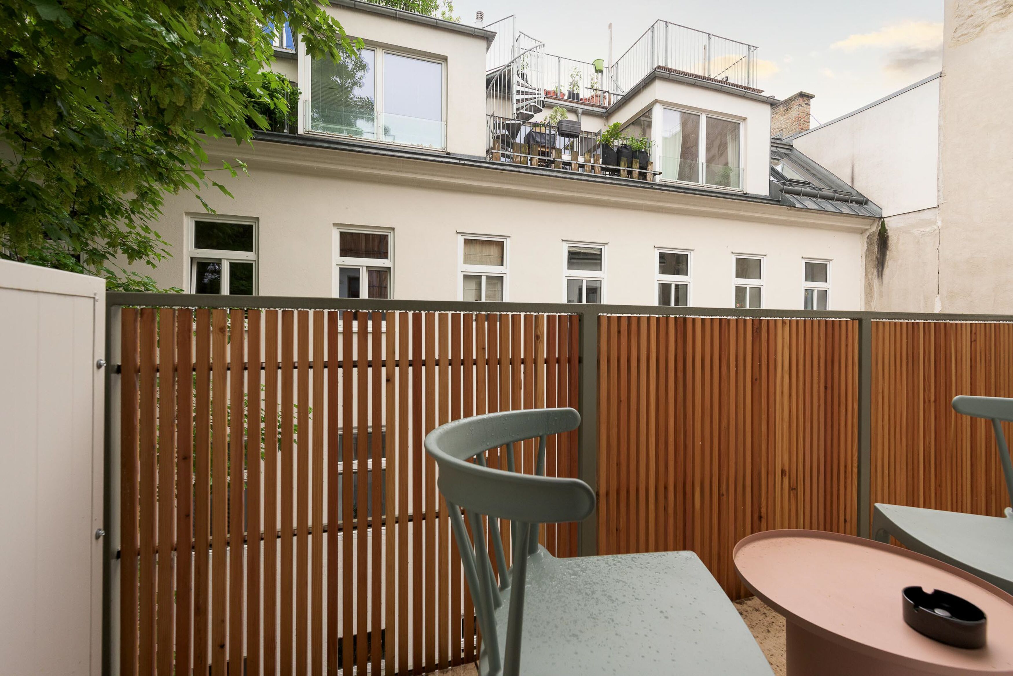 A courtyard with a wooden fence, a table, and a chair.